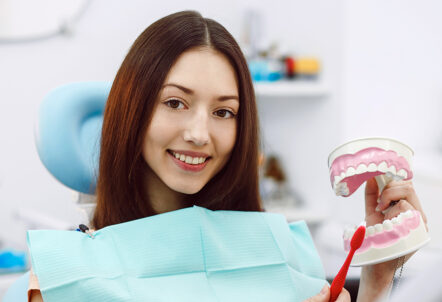 Girl holding a tooth model & doing a tooth brush